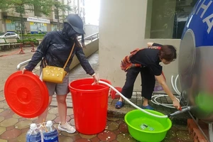 Người dân sống tại chung cư VOV (quận Nam Từ Liêm) lấy nước sạch mua từ xe téc để ăn uống, nấu cơm. Ảnh: AH