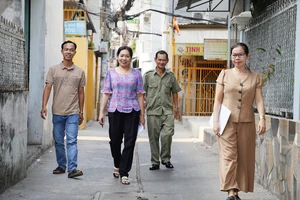 Bà Mai Thị Lệ, Trưởng khu phố 16, phường Bình Hưng Hòa A, quận Bình Tân (thứ hai từ trái sang) cùng cán bộ khu phố đi phổ biến kết quả sắp xếp khu phố, ấp đến người dân địa phương. Ảnh: THUẬN VĂN