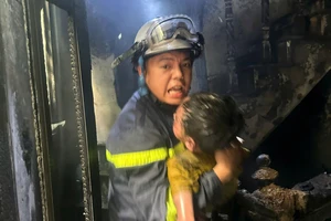 Cảnh sát bế một em nhỏ thoát khỏi vụ cháy nhà ở Hà Nội