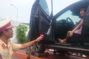 Xe cẩu chở ô tô cùng nữ tài xế cố thủ bên trong về đồn