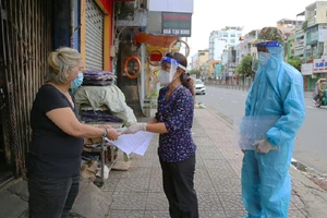 Cán bộ phường 15, quận Bình Thạnh, TP.HCM trao tiền hỗ trợ đợt 2 cho người dân. Ảnh: HOÀNG GIANG