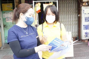 nhân viên bưu điện tư vấn người dân về những quyền lợi khi tham gian BHXH tự nguyện. Ảnh: NGUYỄN HIỀN