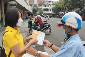 Nhân viên bưu điện tư vấn người dân về quyền lợi khi tham gia BHXH BHYT hộ gia đình. Ảnh: NGUYỄN HIỀN