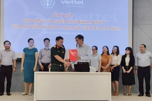 Đại diện BHXH và Viettel TP.HCM ký hợp đồng ủy quyền thu BHXH tự nguyện, BHYT hộ gia đình. Ảnh: NGUYỄN HIỀN 