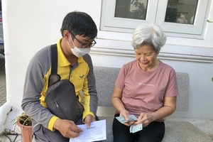Nhân viên bưu điện chi trả lương hưu bằng tiền mặt tại nhà cho người hưởng lương hưu. Ảnh: TM
