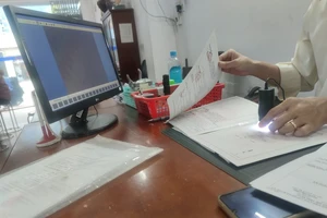 Công chứng viên đang kiểm tra giấy tờ bất động sản. Ảnh: NGUYỄN HIỀN