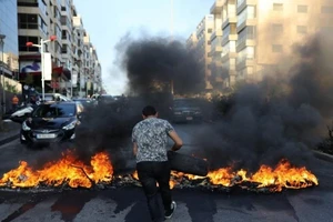Một người đàn ông đốt lốp xe trong cuộc biểu tình ở thủ đô Beirut nhằm phản đối điều kiện sống tồi tệ ở nước này vào ngày 28-6.