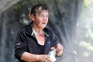 Một phụ nữ người vô gia cư đứng dưới hệ thống phun sương và làm mát tự chế mà một người dân thiết lập ở sân trước của họ ở bang Washington, Mỹ, ngày 28-6.