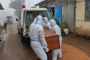 Các tình nguyện viên đưa thi thể của một nạn nhân nhiễm COVID-19 bên trong một chiếc hòm lên xe cứu thương.