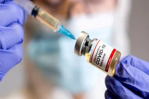 Nhân viên y tế cầm một lọ vaccine ngừa COVID-19.