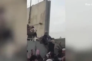 Một bé gái Afghanistan được nhấc qua bức tường cao và được đưa vào sân bay Kabul.