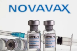Các lọ vaccine ngừa COVID-19 xếp phía trước logo tập đoàn công nghệ sinh học Mỹ Novavax.