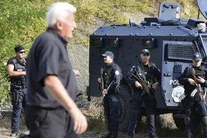 Các sĩ quan cảnh sát đặc nhiệm Kosovo đứng gác khi hàng trăm người Serbia ở Kosovo phản đối lệnh cấm đối với các phương tiện mang biển đăng ký Serbia, ngày 27-9.