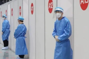 Nhân viên y tế đứng chờ bên ngoài trung tâm tiêm chủng ở Bắc Kinh, Trung Quốc, ngày 15-4.