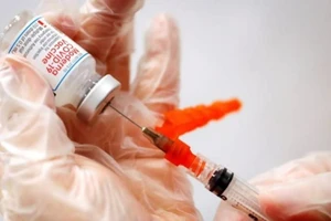 Nhân viên y tế lấy vaccine Moderna từ lọ.