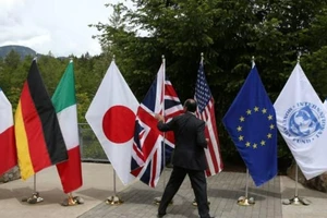 Một đại biểu nắm lấy một lá cờ để ngăn nó bị gió thổi bay tại Hội nghị thượng đỉnh các nước nhóm G7 ở Whistler, Canada, vào ngày 31-5-2018.