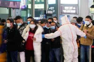 Nhân viên bảo vệ chặn lối ra trong lúc hướng dẫn người dân quét mã QR để khai báo tình trạng sức khỏe của họ tại ga xe lửa Hồng Kiều ở Thượng Hải, Trung Quốc, ngày 25-11.