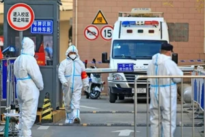 Công nhân mặc đồ bảo hộ đứng ở lối vào khu kí túc xá của một trường đại học ở Tây An, Trung Quốc vào ngày 20-12.