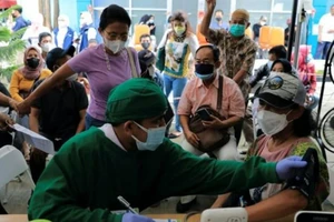 Nhân viên y tế thực hiện kiểm tra sức khỏe cho một phụ nữ trước khi tiêm mũi tăng cường ở Jakarta, Indonesia, ngày 12-1.