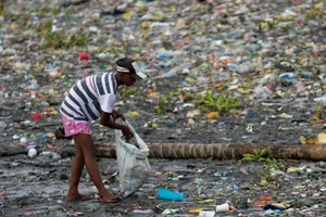 Một người phụ nữ nhặt những chiếc cốc nhựa dọc theo bờ sông Pasig đầy rác thải ở Manila, Philippines, ngày 10-6-2021.