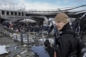 Người dân Ukraine đi bộ dưới một cây cầu bị phá hủy trong khi chạy trốn khỏi cuộc xung đột vào ngày 8-3.