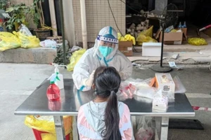 Nhân viên y tế lấy mẫu xét nghiệm COVID-19 cho một bé gái ở Trung Quốc.