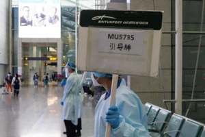 Một tiếp viên hàng không đang giơ bảng hướng dẫn thân nhân của hành khách trên chuyến bay China Eastern MU5375 bị rơi vào ngày 21-3.