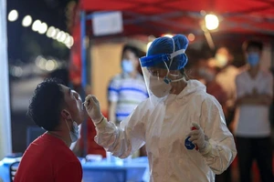 ​Nhân viên y tế lấy mẫu xét nghiệm từ một người đàn ông ở TP Vũ Hán, tỉnh Hồ Bắc, Trung Quốc vào ngày 5-8-2021.