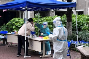 Nhân viên y tế đang lấy mẫu xét nghiệm cho một người đàn ông ở Thượng Hải, Trung Quốc ngày 14-4. 