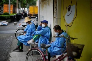 Công nhân mặc đồ bảo hộ nghỉ ngơi trên đường phố trong bối cảnh dịch bùng phát ở TP Thượng Hải, Trung Quốc, ngày 28-5.