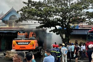 Xe máy xúc phá cửa để dập đám cháy ở kho chứa dép