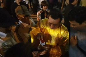 Đóng ấn giả vào tay du khách ở đền Trần trước giờ khai ấn