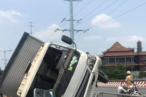 Ô tô tải lao vào làn xe máy, lật trên cầu Bình Lợi