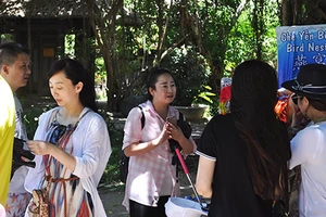 Một nữ HDV người Trung Quốc (mặc áo ca rô) đang giới thiệu cho một đoàn khách nước này tại một điểm du lịch ở Nha Trang. Ảnh minh họa: TẤN LỘC