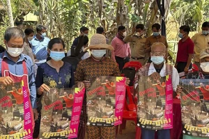 Người dân Campuchia cầm áp phích tuyên truyền về mối đe dọa của cúm gia cầm H5N1 ở tỉnh Prey Veng ( Campuchia) ngày 23-2. Ảnh: AP