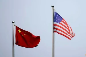 Quốc kỳ Trung Quốc và Mỹ tung bay bên ngoài một tòa nhà ở Thượng Hải (Trung Quốc). Ảnh: REUTERS