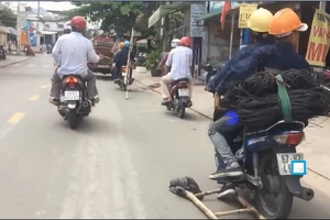 Tay lái xe, chân móc thang tre dài ngoằng trên phố