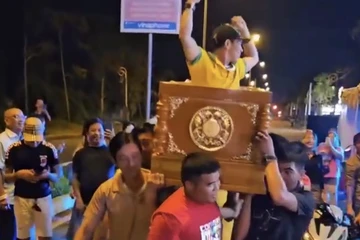 Nhóm người mặc áo trại hòm khiêng quan tài có người sống, nhảy múa trên đường