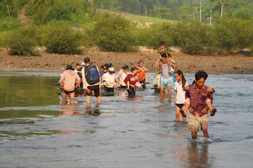 Bám lưng cha mẹ vượt sông đến trường