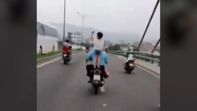 Để con đứng trên yên, không đội mũ bảo hiểm khi xe đang chạy