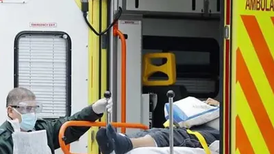 Một thành viên của dịch vụ xe cứu thương hỗ trợ chuyển một bệnh nhân đến Bệnh viện St Thomas ở London. Ảnh: AFP