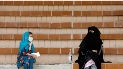 Một phụ nữ và một bé gái Pakistan giữ khoảng cách an toàn khi đang ngồi đợi kết quả xét nghiệm COVID-19 tại một điểm xét nghiệm ở thành phố Karachi, Pakistan. Ảnh: REUTERS