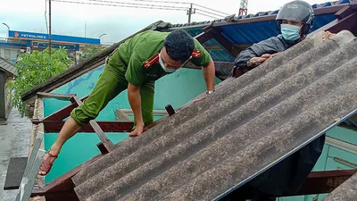 Công an, chính quyền UBND xã Phong Hải, huyện Phong Điền (Thừa Thiên-Huế) hỗ trợ người dân lợp lại nhà.