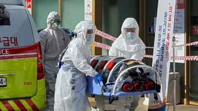 Nhân viên y tế di chuyển một người nghi nhiễm COVID-19 ở TP Daegu hôm 21-2. Ảnh: AFP