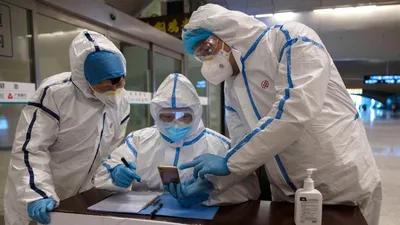 Nhân viên y tế kiểm tra lịch sử đi lại của hành khách tại một nhà ga ở TP Vũ Hán, Trung Quốc ngày 29-3. Ảnh: REUTERS