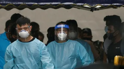 Các nhân viên tuyến đầu tại Singapore mặc đồ bảo hộ đưa một nhóm lao động nhập cư đi cách ly tập trung. Ảnh: REUTERS