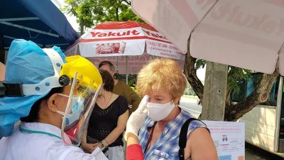 Nhân viên y tế đo thân nhiệt cho một du khách nước ngoài tại điểm chốt ra vào thành phố Đà Nẵng. Ảnh: T.AN 