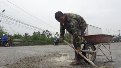 Người đàn ông chở đá vá ổ gà trên quốc lộ 