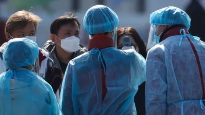 Nhân viên mặc đồ bảo hộ đo thân nhiệt hành khách trước khi họ lên xe buýt gần du thuyền Diamond Princess bị cách ly tại cảng Yokohama, Nhật Bản.