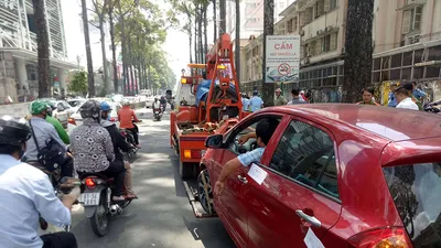 Bị cẩu xe, tài xế cố thủ ngồi hút thuốc trong cabin